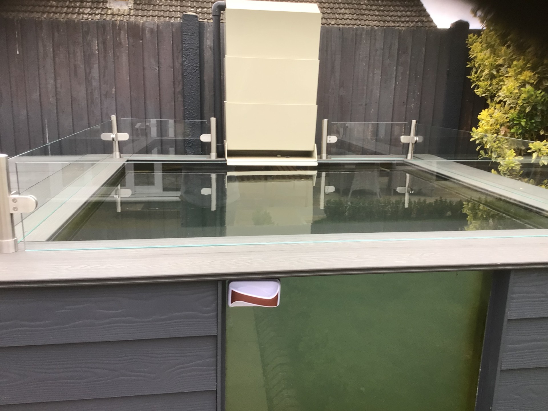 Close-up of glass jump guard installed on modern raised koi pond with viewing window