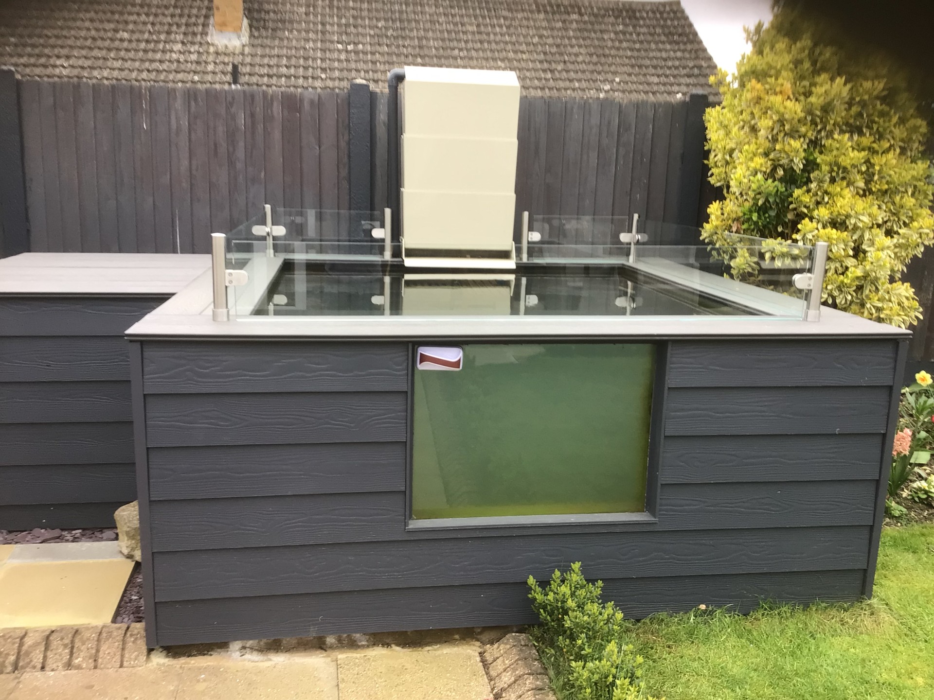 Modern composite-clad raised koi pond with glass jump guard and viewing window